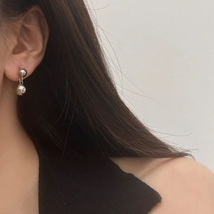 Close-up of model wearing silver double ball dangle earrings with a polished metallic finish