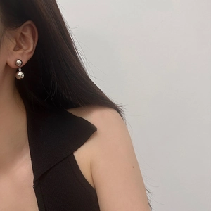 Close-up of minimalist silver double-sphere drop earrings worn by a model
