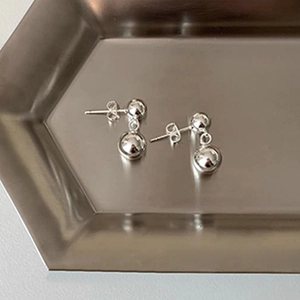 Detail of silver double ball earrings showing the smooth metal finish and butterfly back