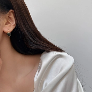 Elegant heart-shaped drop earrings with gold trim worn by a model on a white background