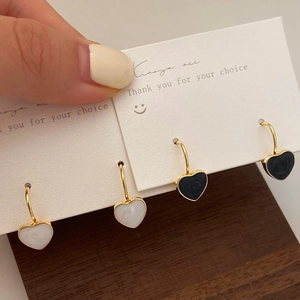 Detailed close-up of heart dangle earrings featuring marble texture and golden hooks