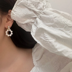 Elegant gold freshwater pearl earrings with zircon stones worn on model's ear