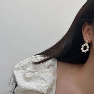 Close-up of elegant freshwater pearl hoop earrings with zircon studs on a model