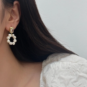 Detail of freshwater pearl hoop earring with zircon stud on model's ear in close-up