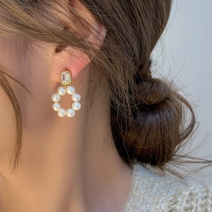 Close-up of elegant freshwater pearl hoop earrings with a sparkling zircon stud on model
