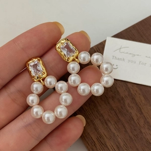 Macro detail of freshwater pearl hoop earrings with gold texture and zircon stones