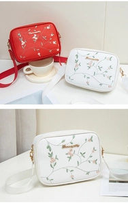 Close-up of elegant floral embroidery and metal logo on a stylish crossbody camera bag