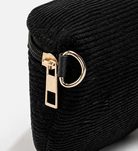 Detailed macro view of black corduroy fabric texture and matte gold zipper hardware