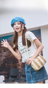 Vertical striped straw camera bag with beige strap and metal zipper on model
