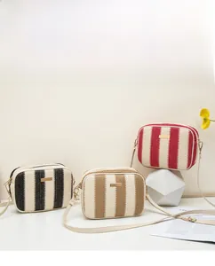Detail view of woven straw camera bags with vertical stripes and gold metal hardware