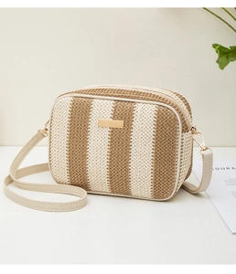 Detail of woven straw camera bag with beige stripes, gold hardware and leather strap