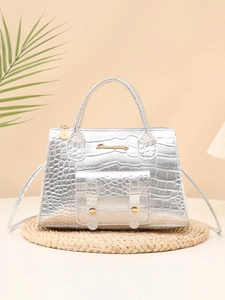 Detail of silver croco-embossed handbag with gold hardware on a stylish woven mat