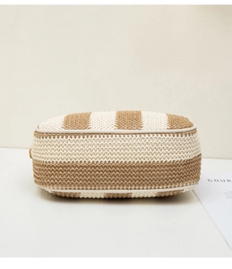 Close-up of woven straw camera bag featuring beige stripes and golden metal hardware
