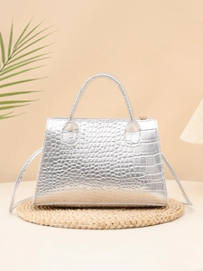 Detail of silver crocodile pattern handbag with metallic finish and top handle