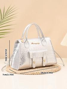 Detailed view of silver crocodile pattern bag with gold metal logo and side buckles