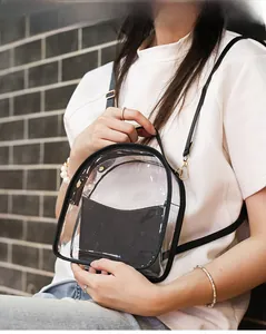 Detailed view of transparent PVC mini backpack with black trim held by a model