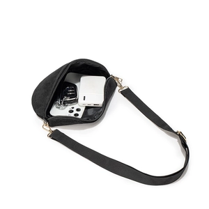 Minimalist black corduroy half-moon crossbody bag showing interior storage capacity