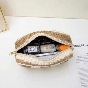 Women's woven straw camera shoulder bag with gold zipper showing spacious interior storage