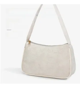 Detail view of beige suede baguette bag featuring white leather trim and gold zipper