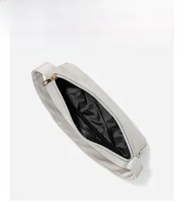 Interior detail of a gray minimalist handbag showing black lining and gold zipper