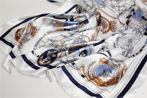 Detailed close-up of nautical silk scarf featuring navy anchors and orange sailing patterns