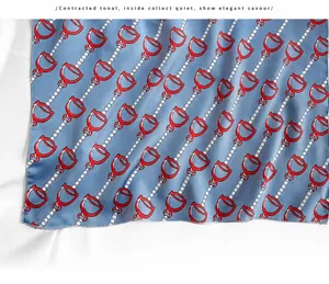 Close-up of blue-grey silk scarf with red horsebit pattern and detailed edge stitching