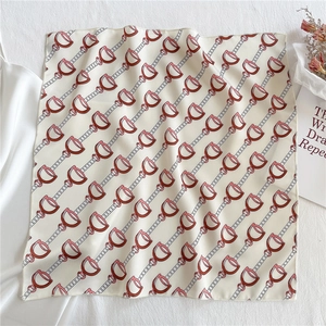 Detail of square silk scarf with red horse-bit pattern on creamy white fabric