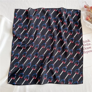 Detailed view of square satin scarf with equestrian patterns and horseshoe prints