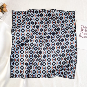 Flat lay of geometric pattern silk scarf with professional lock-stitch hem and floral decor