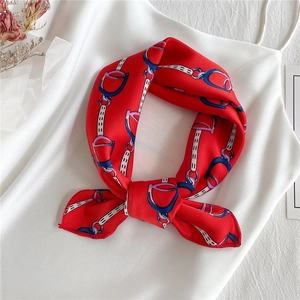 Close-up of red satin scarf tied in a bow with classic chain and horsebit print