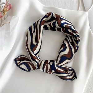 Detailed view of knotted silk-like square scarf with abstract wavy patterns and hemmed edges
