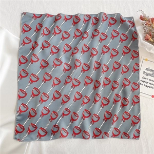 Detail of grey silk square scarf with red stirrup and chain patterns in a lifestyle setting