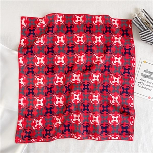 Detail of red geometric silk scarf with chain pattern on a textured white background