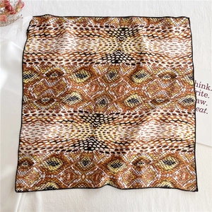 Detail showing the snake print silk scarf texture and fine black stitched edges