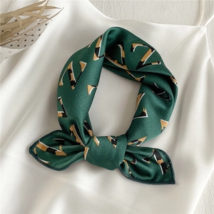 Detail of a dark green satin scarf with geometric patterns knotted on a white silk camisole