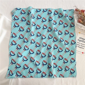Close-up of light blue silk square scarf with horse bit pattern and fine machine edge