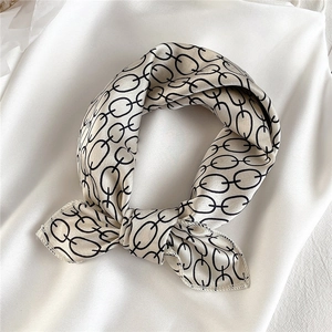 Detail view of champagne silk scarf with black chain pattern and smooth satin texture