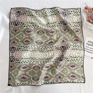 Detail of square satin scarf with green and pink geometric snake print and black stitched edge