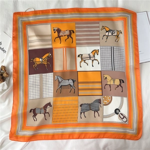 Detailed pattern of orange square silk scarf featuring luxury horse and geometric motifs