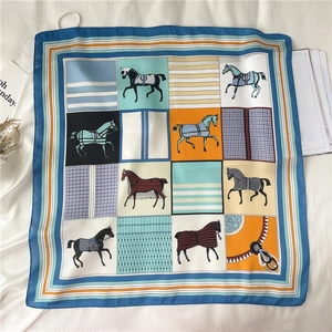 Detailed flat lay of a silk square scarf with vintage equestrian horse and grid patterns