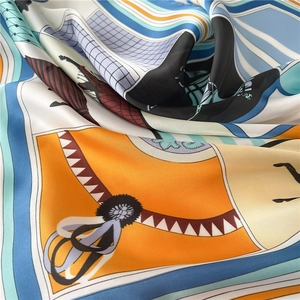 Macro view of satin silk scarf showing geometric prints and vibrant orange blue patterns