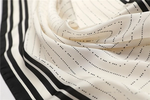 Detail of striped silk-like square scarf featuring geometric patterns and soft draping