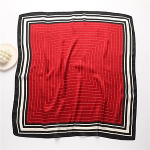 Detail view of the red square silk scarf with bold striped borders and geometric patterns