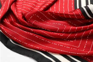 Close-up of red silk scarf with white polka dots and black striped edges