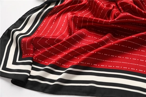 Detailed view of red silk scarf showing geometric patterns and black white striped borders