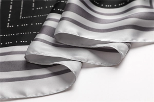 Close-up of black and white striped silk-like scarf showing soft texture and fine hem