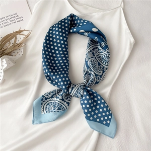 Détail d'un foulard en soie bleu marine avec des pois blancs et des motifs paisley noués