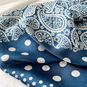 Gros plan d'un foulard en satin bleu marine avec motifs paisley et pois en patchwork