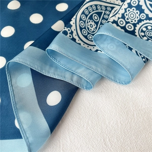 Détail d'un foulard en soie bleue avec pois classiques et motifs paisley complexes