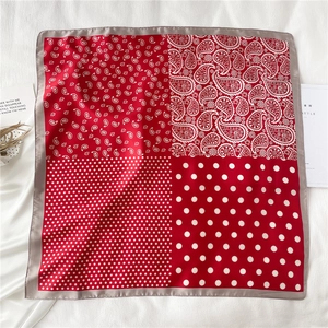 Détail d'un foulard carré rouge à motifs paisley et pois sur un fond de tissu blanc